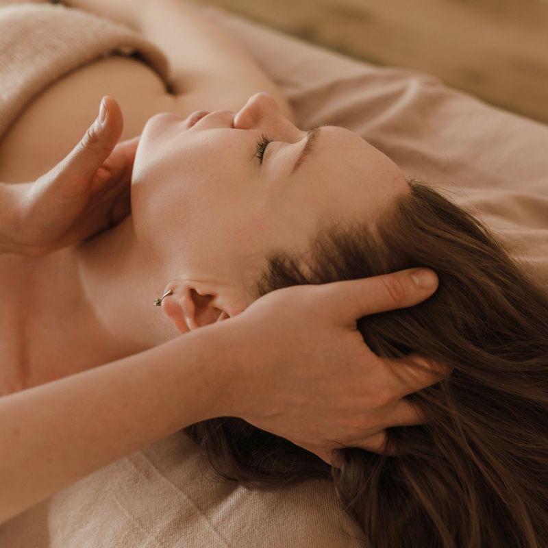Woman receiving relaxing head massage in spa on massage table